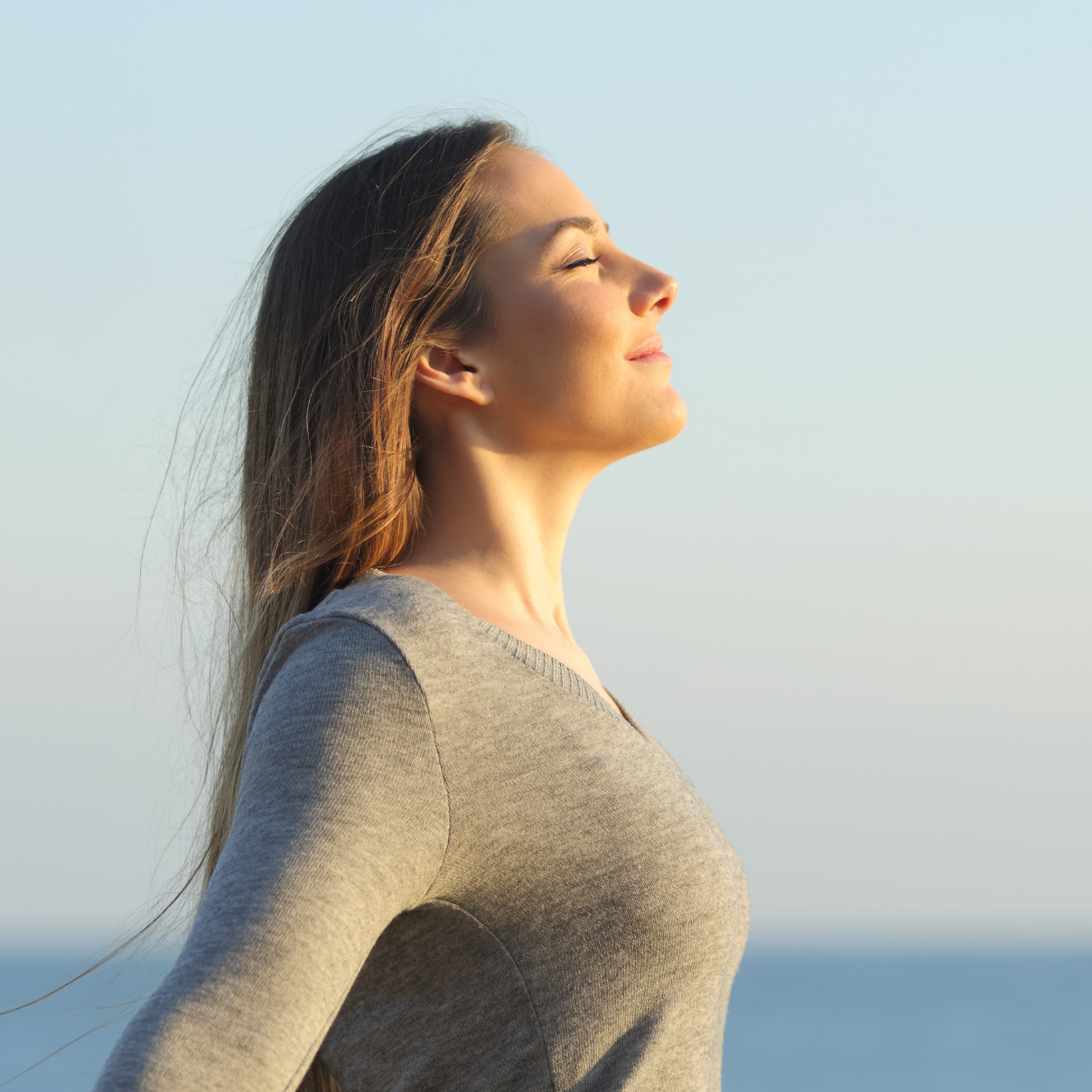 Woman breathing calmly with her eyes closed at sunrise